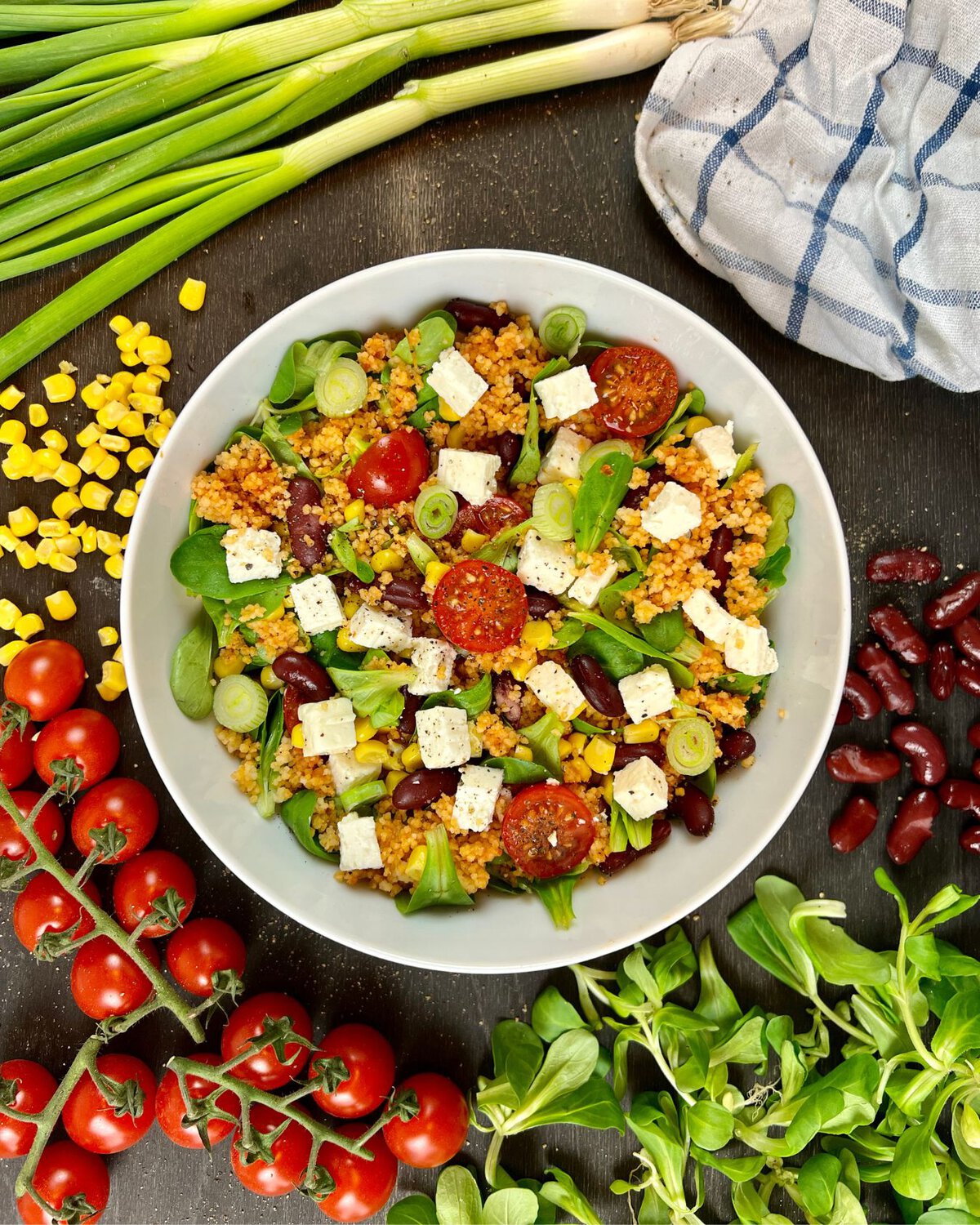 Ein einfacher Couscous-Feldsalat mit Feta in einer Schüssel bestehend aus Couscous, Kirschtomaten, Fetakäse, Kidneybohnen und Frühlingszwiebeln.