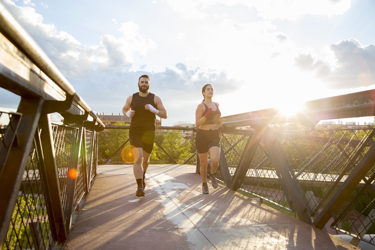 Junges Paar das auf einer Bruecke joggt Junges Paar, das auf einer Brücke joggt