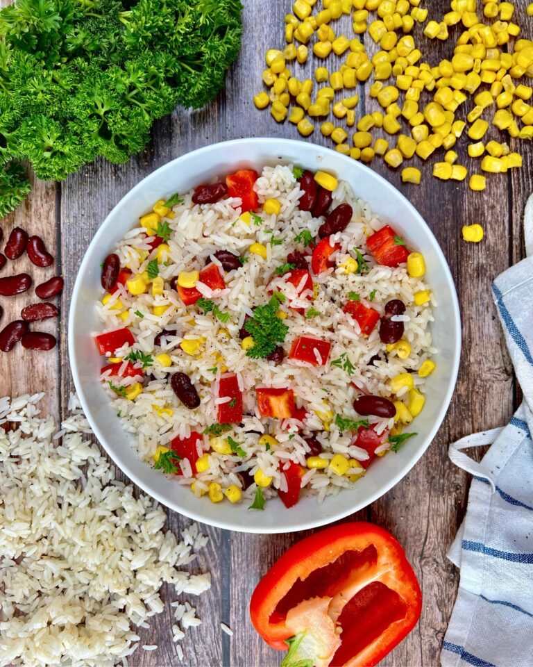 Eine Schüssel mit farbenfrohem Reissalat, mit Paprika, Mais, Kidneybohnen und Petersilie.