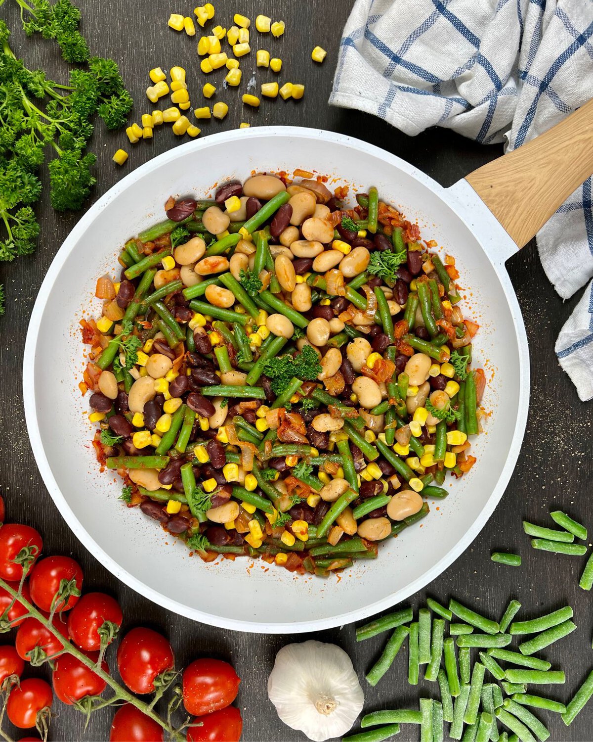 Eine vegetarische Westernpfanne gefüllt mit einem bunten Gemüsemix, bestehend aus grünen Bohnen, Mais, Kidneybohnen, weißen Bohnen und Brechbohnen.